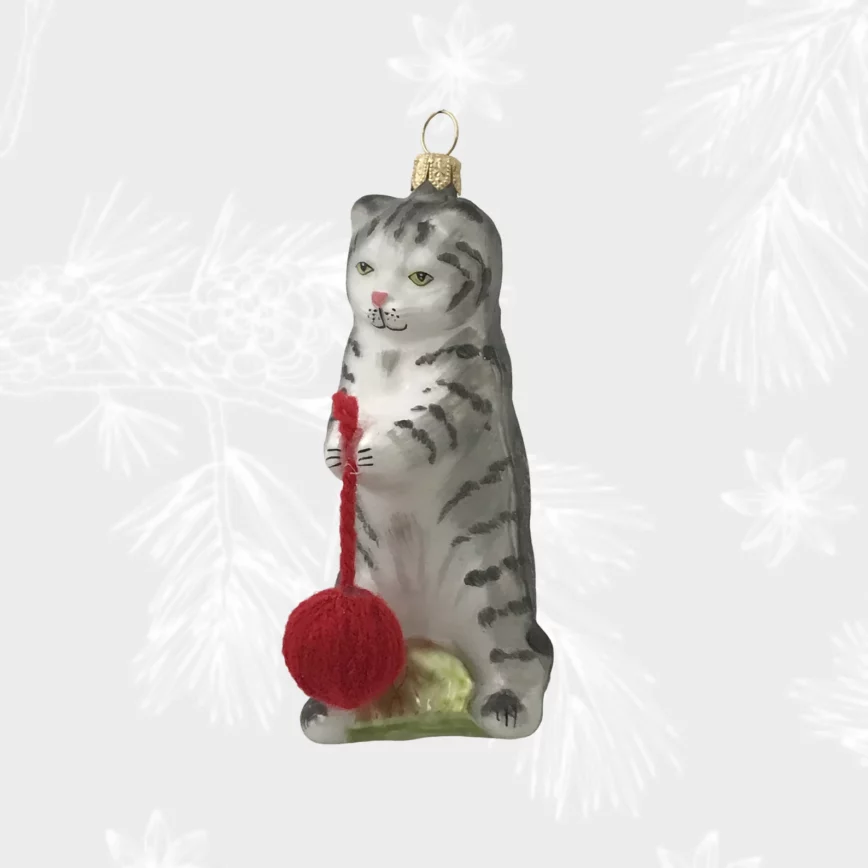 une boule de noel en forme de chat qui tient une pelote de laine